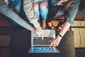 aerial view of three people pointing at laptop screen