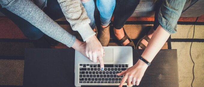 aerial view of three people pointing at laptop screen