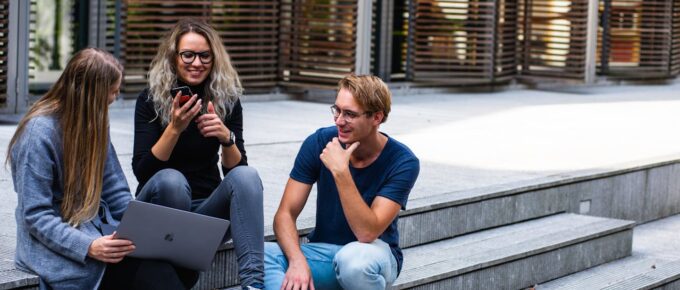three people sitting on stairs with laptop