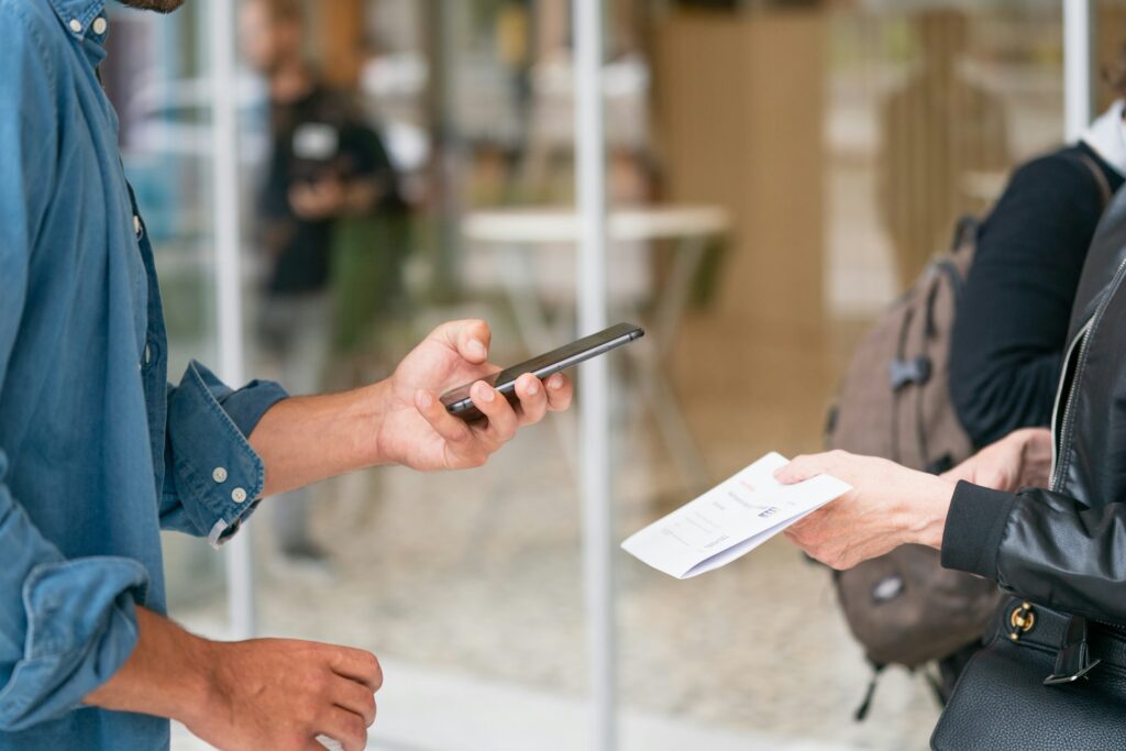 Person holding smartphone in front of person with paper