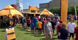 Fans crowding around a branded sports sponsorship activation tent at an outdoor live event on a sunny day