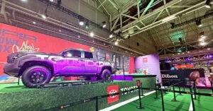 Toyota pickup truck displayed on a turf platform at an interactive Super Bowl fan experience activation, with stanchions guiding fans through the setup.